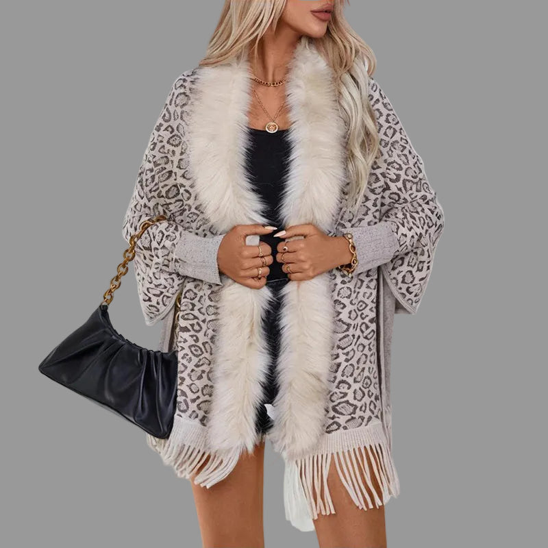 Woman wearing a leopard print poncho with a fur scarf and holding a black handbag.