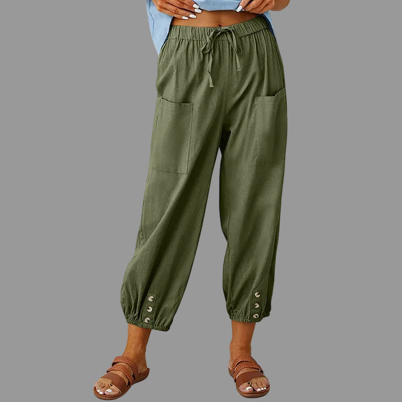 Person wearing olive green pants with button details against a wooden background